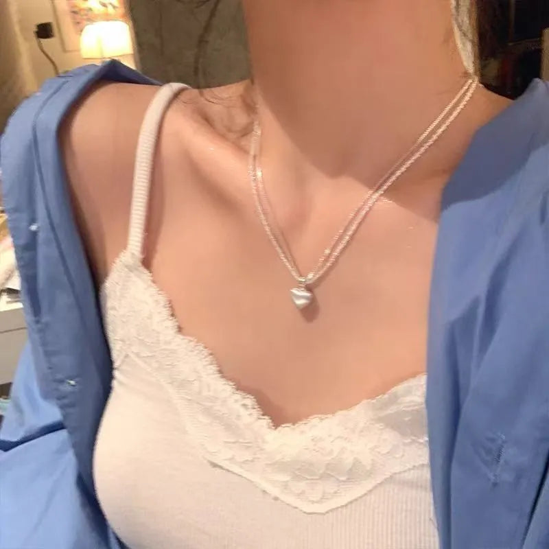 Brushed double-layer heart pendant necklace with adjustable chain on white background