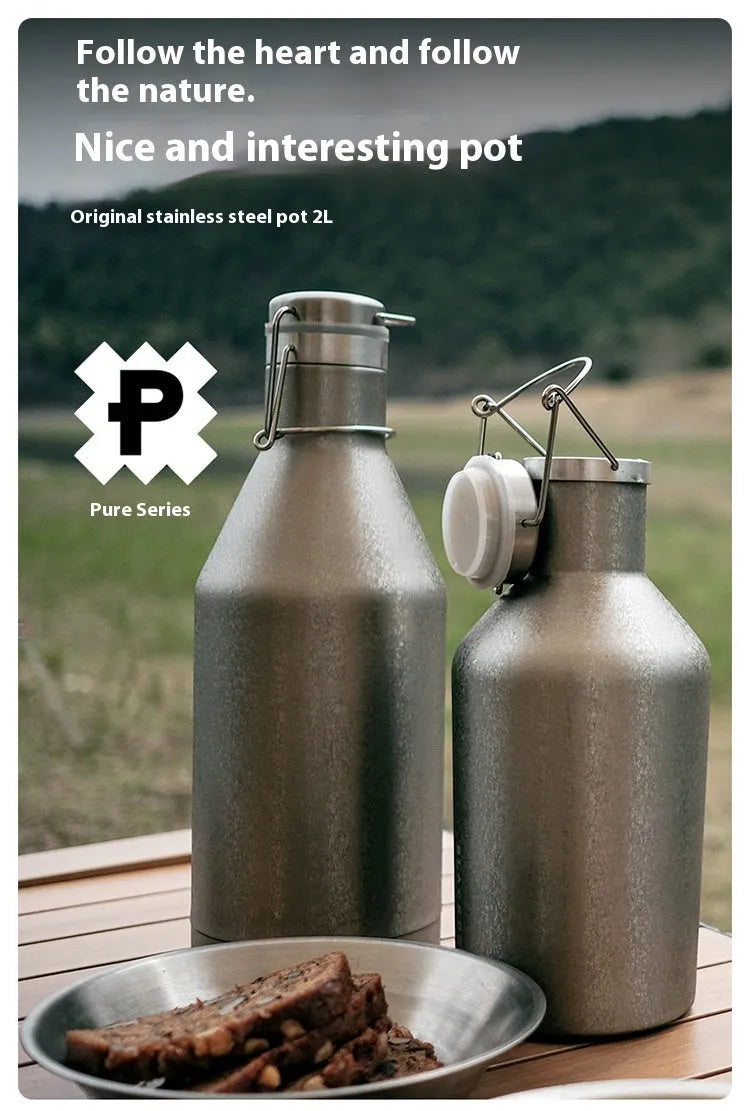 Large stainless steel outdoor thermal pot with a handle, shown in a natural setting.