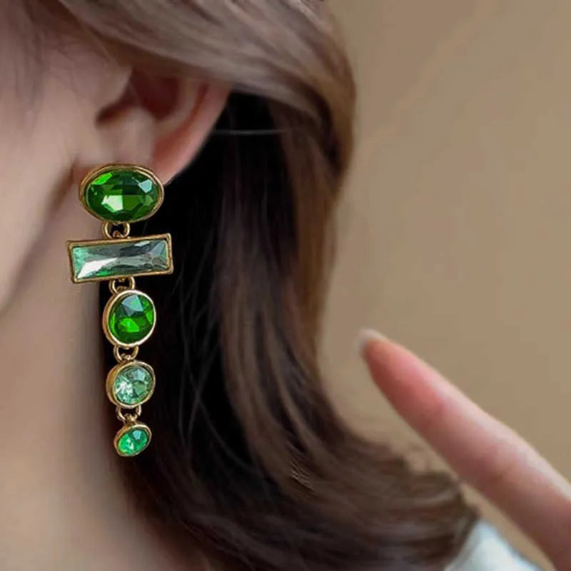 Green gradient tassel drop earrings with geometric alloy shapes and inlaid zircon stones on a white background.