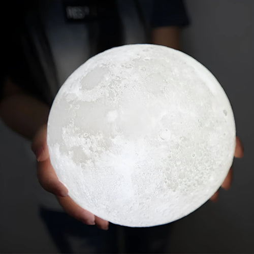 3D printed white moon lamp with detailed lunar surface texture on a wooden holder.