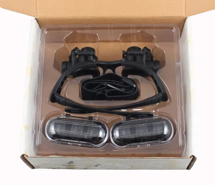 Black double eye magnifying glasses with LED lights and interchangeable lenses on a headband.