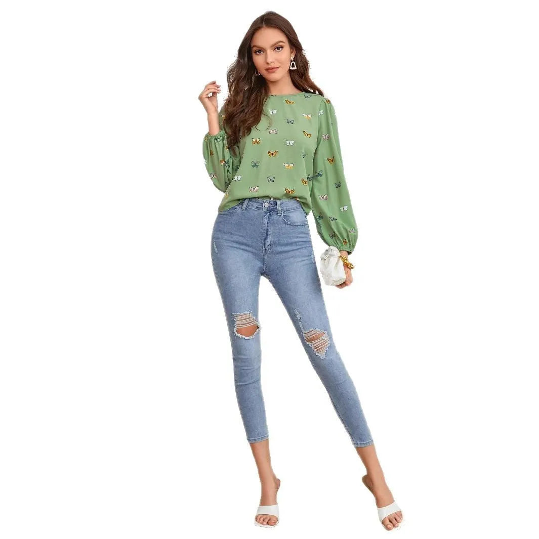 Green women's long-sleeved shirt with butterfly print, showing loose fit and long sleeves.