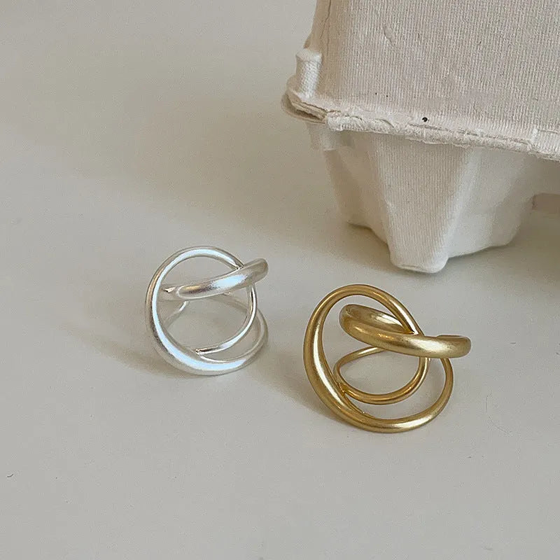 Geometric open ring with interlaced matte metal design in gold or silver plating.