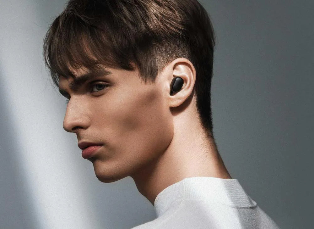 Black Redmi AirDots true wireless earbuds next to their compact charging case.