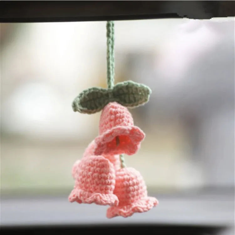 Green and white knitted wool car plant ornament hanging from a rope
