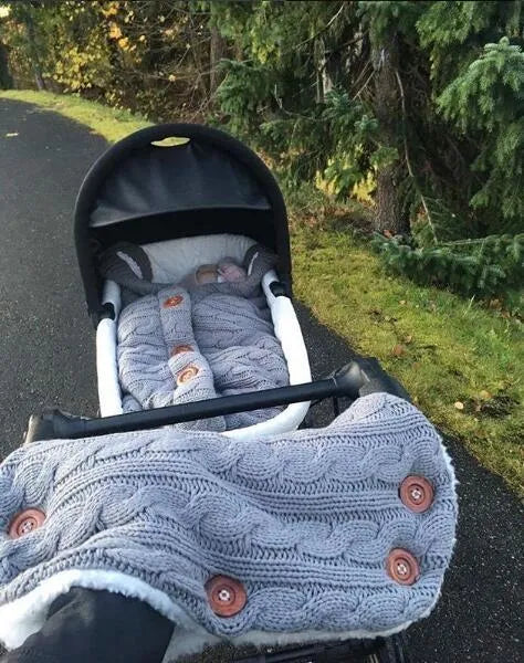 Baby sleeping bag in beige with lamb wool and acrylic material, button opening, and matching gloves on pram