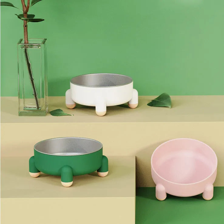 Green stainless steel pet bowl with non-slip base and raised high foot on a wooden floor.