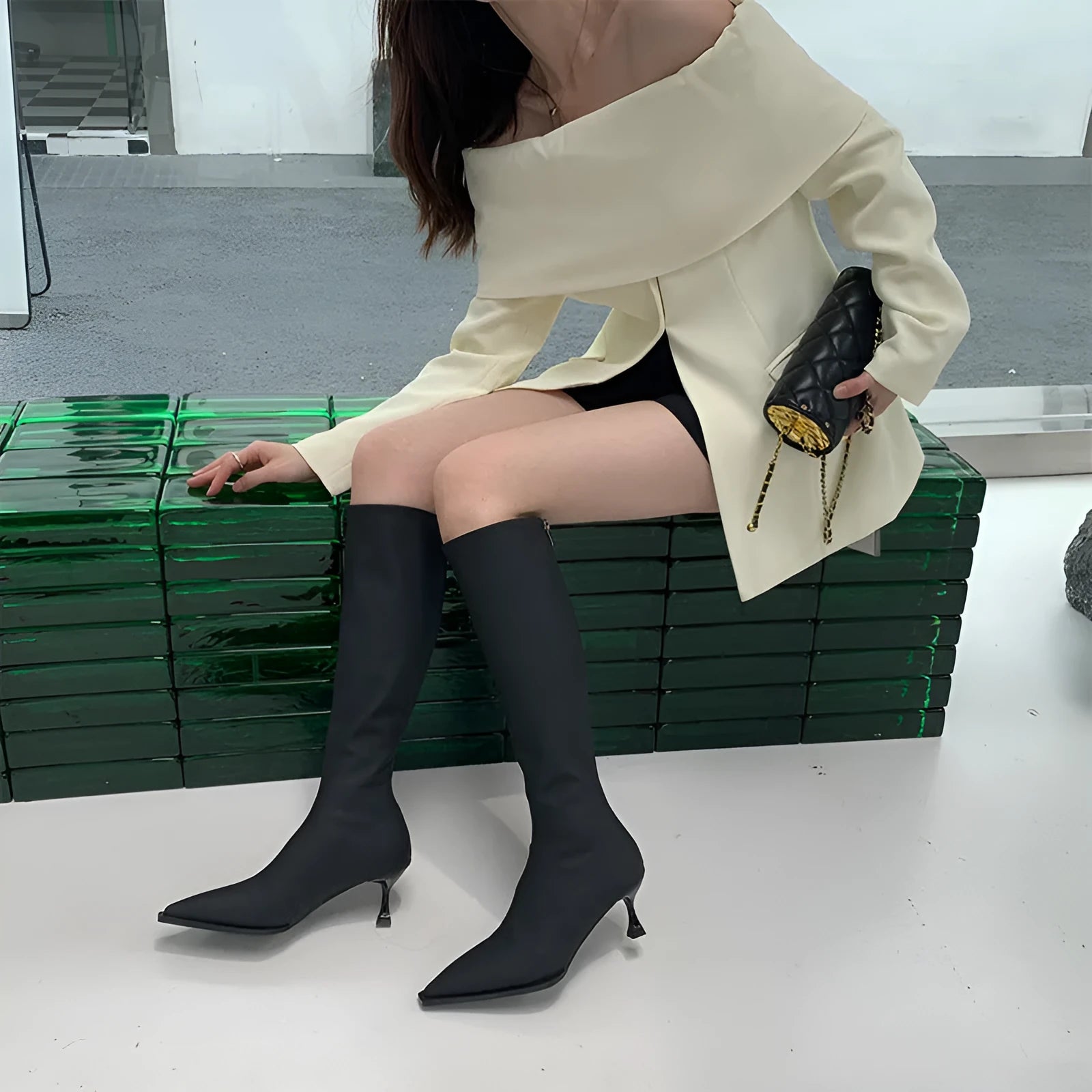 Women's black pointed toe stiletto boots with a back zipper, shown from the side.