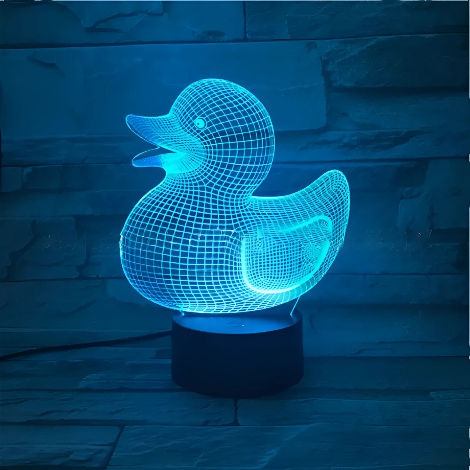Little yellow duck 3D night light on a table with remote control, displaying a blue colour.