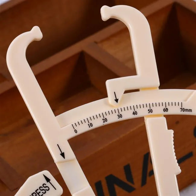 Acrylic skin fold caliper body fat measuring instrument showing scale and measurement jaws