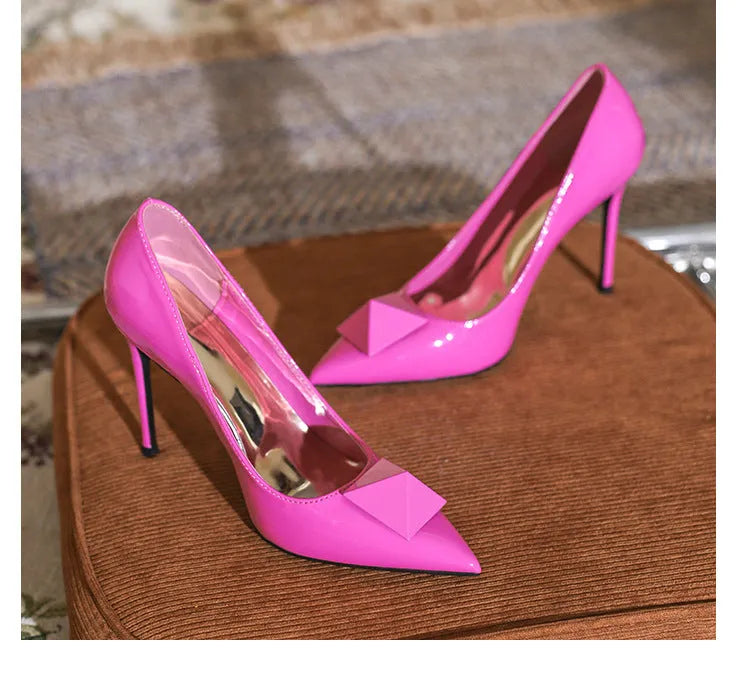 Pink patent leather women's stiletto heels with pointed toe, rivet detail, and an adjustable ankle buckle.