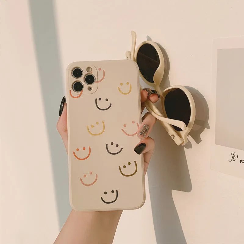 Simple silicone TPU iPhone case with a painted smiley face design on a solid colour background.