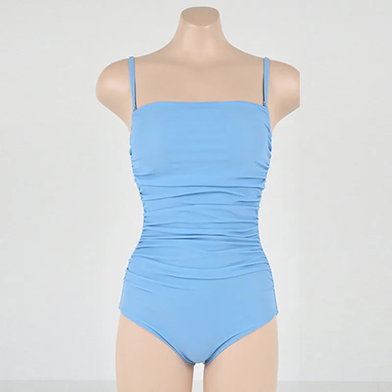 Blue sling style one-piece swimsuit with belly pleats and slim fit on model.