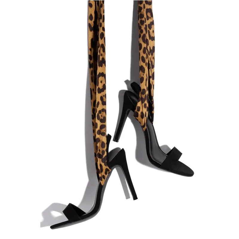 Light brown women's high heels with leopard print, thin ankle straps, and a tall stiletto heel on a plain background.