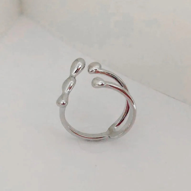 Gold brass opening ring with sphere design on a white background.