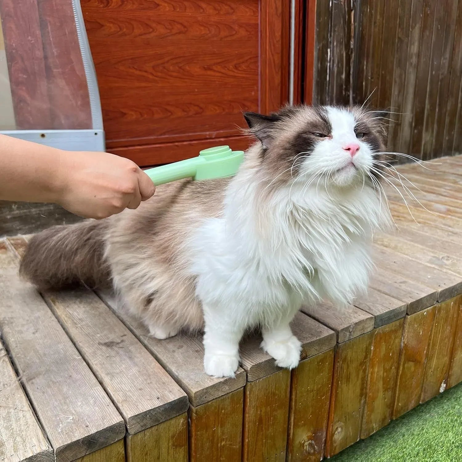 Green and yellow pet grooming brush with stainless steel comb for cats and dogs, showing hanging loop and curved teeth design