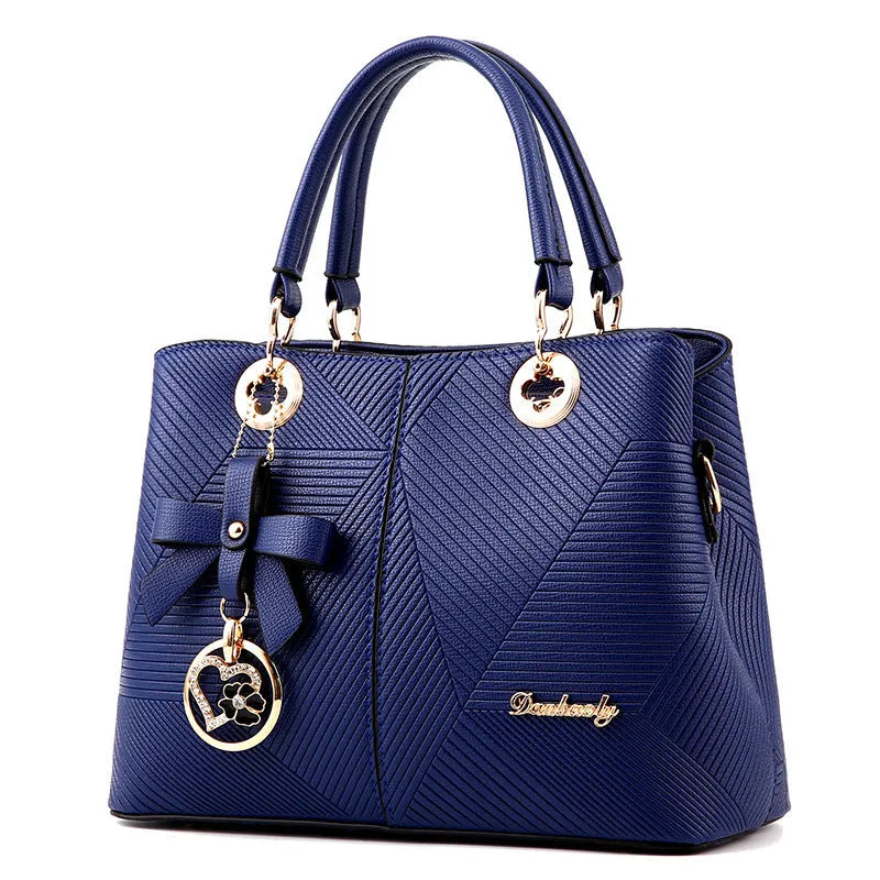A structured navy blue PU leather crossbody bag with a gold zip, shown on a model with an adjustable shoulder strap.