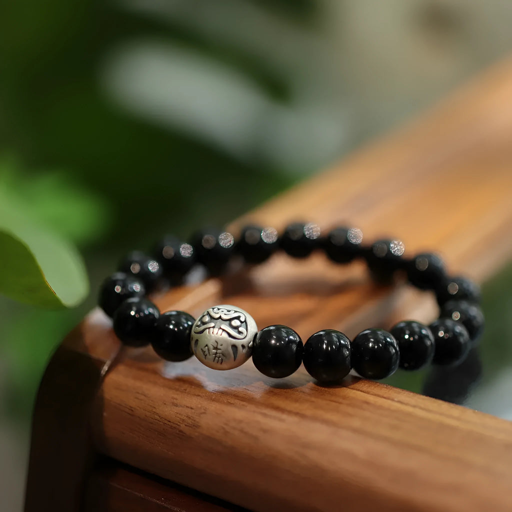 Close-up of a women's bracelet with large black agate beads and a sterling silver clasp on a wrist.