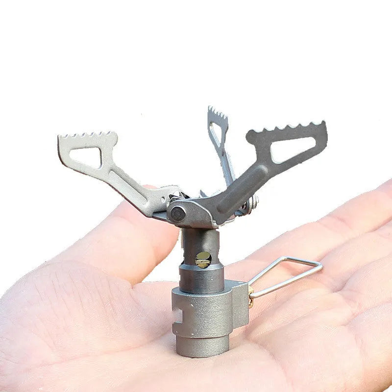 Portable gas camping stove with a one-piece metal furnace body, shown on an outdoor surface.