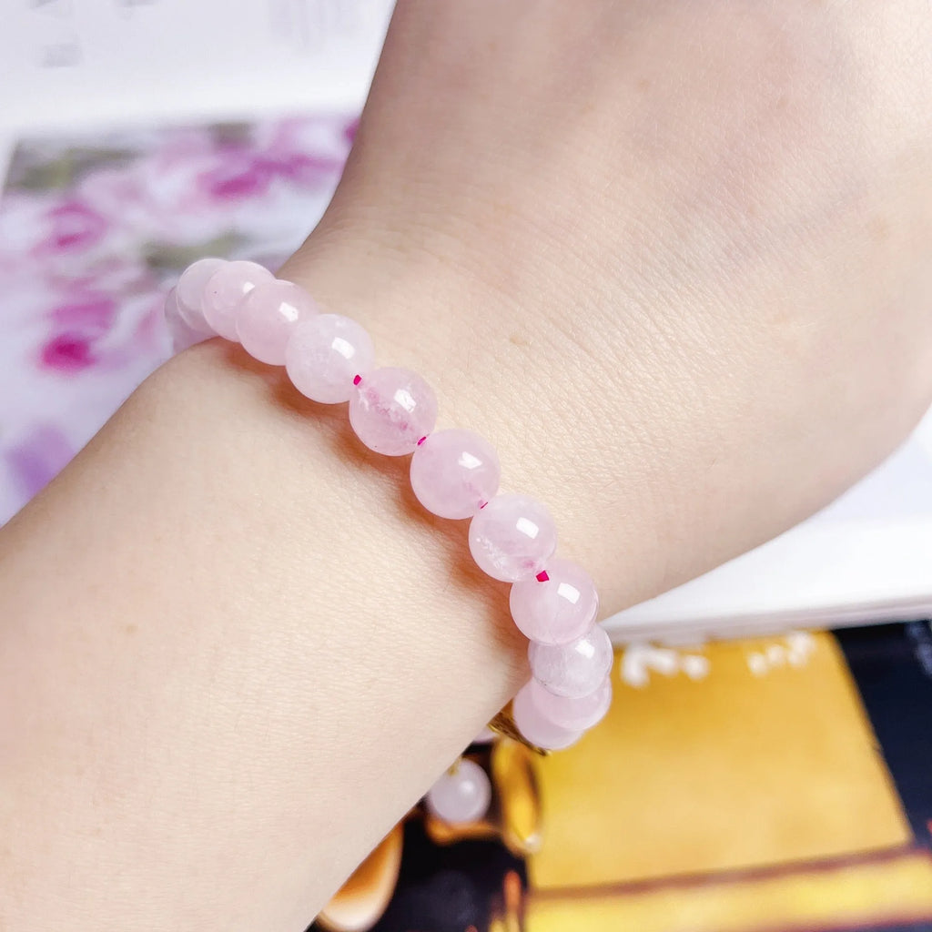 Close-up of a handmade pink crystal peach blossom bracelet on a wrist, showing adjustable closure.
