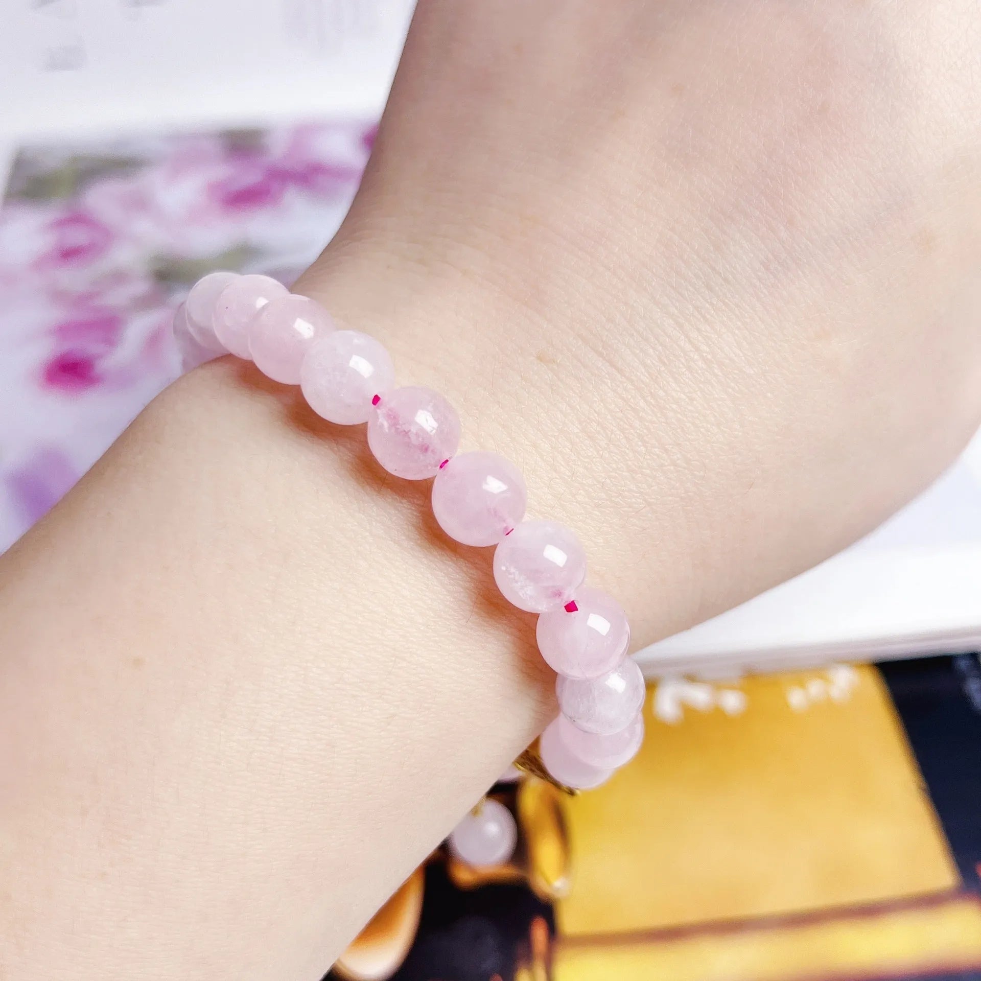 Close-up of a handmade pink crystal peach blossom bracelet on a wrist, showing adjustable closure.