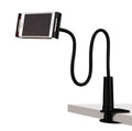 Black bedside phone holder with long arm extended, holding a mobile phone at an angle on a wooden table.