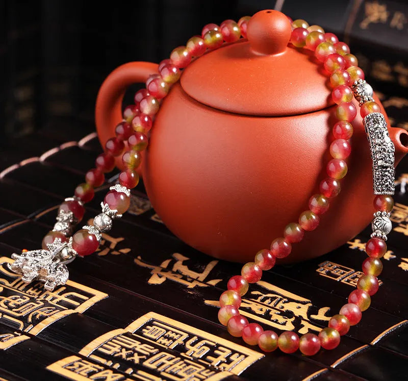 Handmade natural watermelon crystal bracelet with a Chinese knot, showing geometric beads in elephant style.