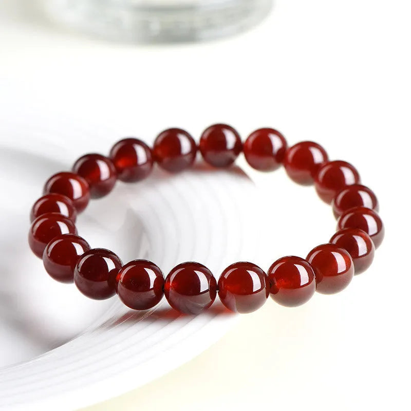 Natural orange red garnet crystal bracelet with ruyi design on a wrist.