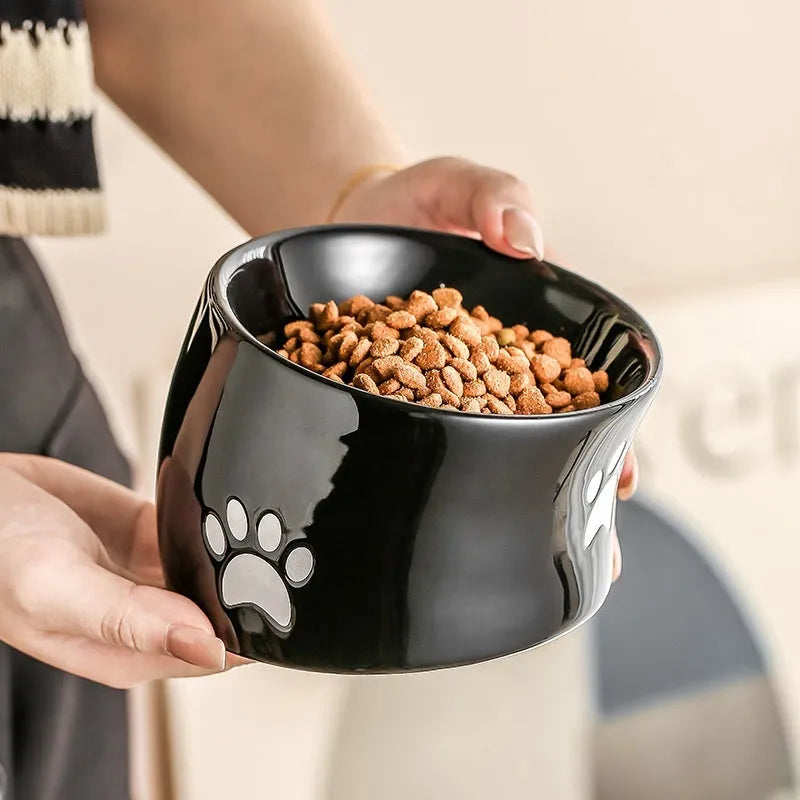 Ceramic cat food bowl with high foot base in a cat's paw print design