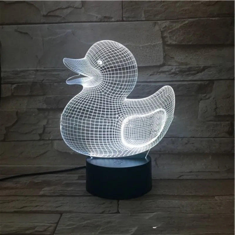 Little yellow duck 3D night light on a table with remote control, displaying a blue colour.