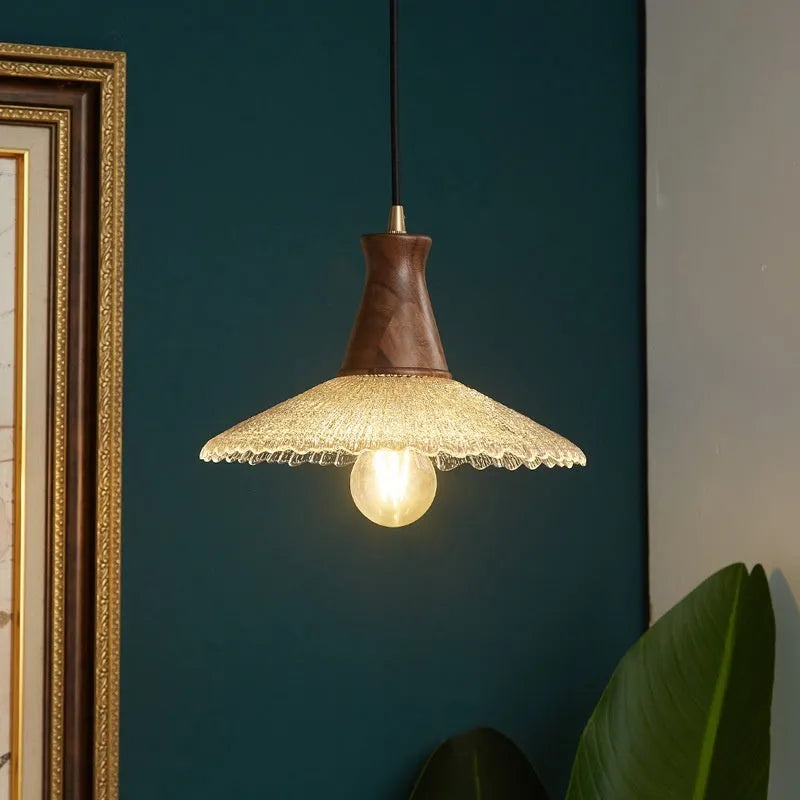 Retro chandelier with wooden body, brass metalwork, and a clear glass shade hanging from the ceiling.