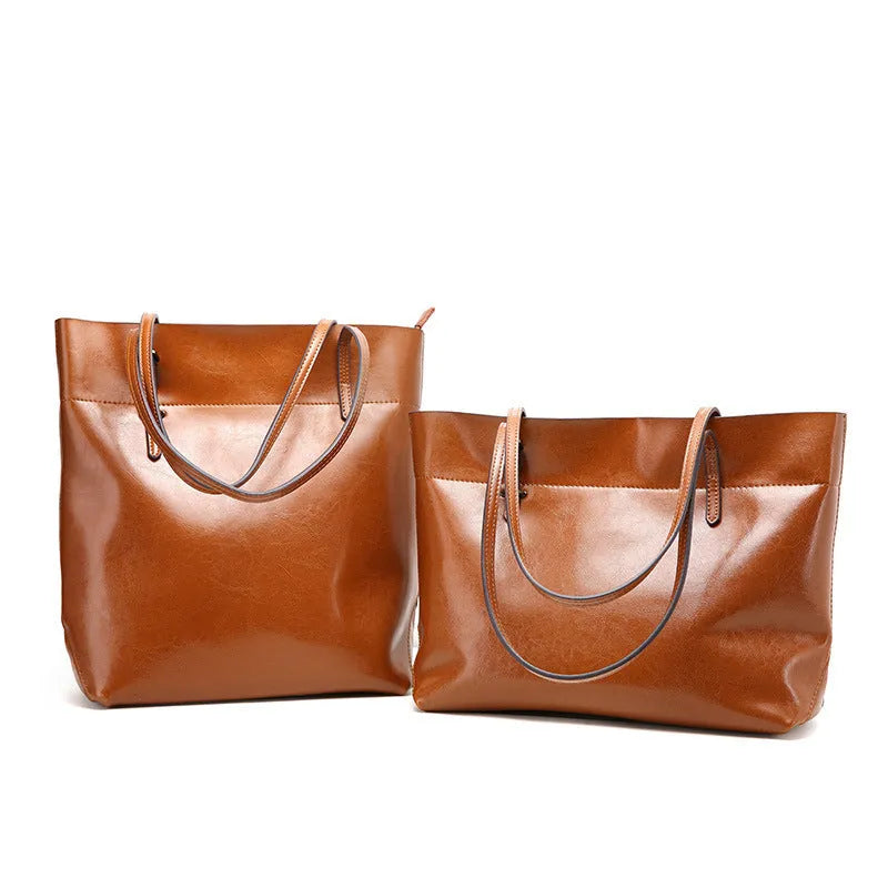 Brown waxed cowhide cross-body handbag with zip, showing two compartments and adjustable strap.