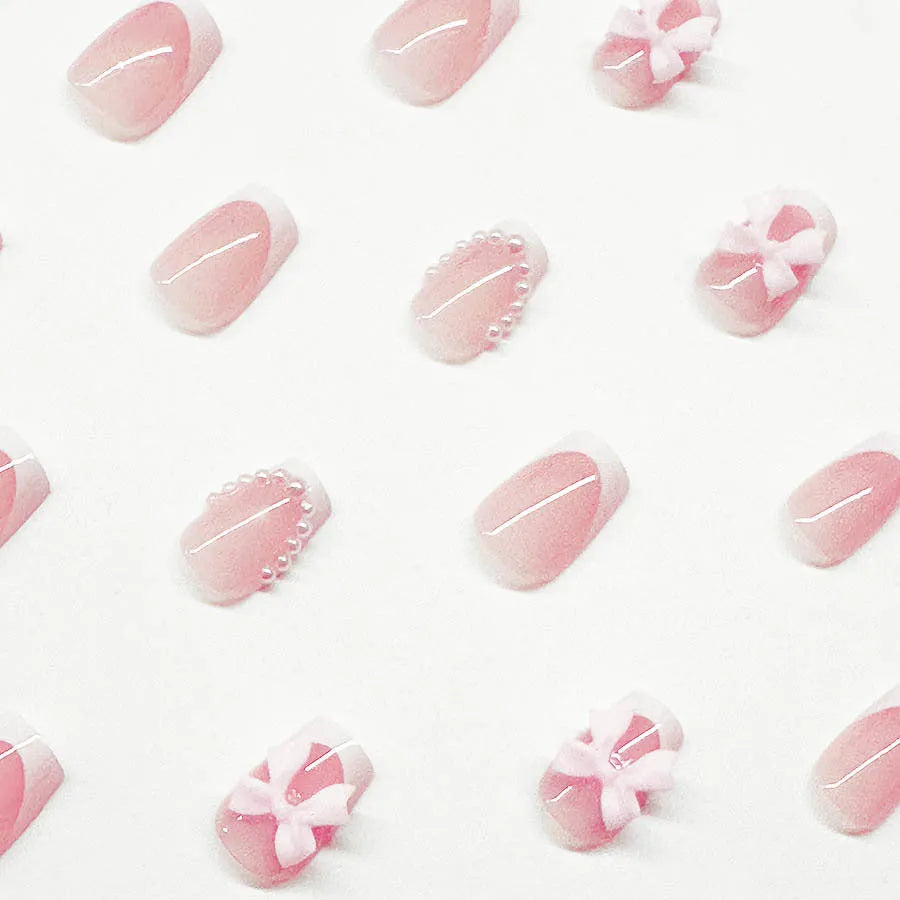 Set of 24 white French manicure false nails with bow and tulip designs, next to bottles of S274 glue and jelly glue.