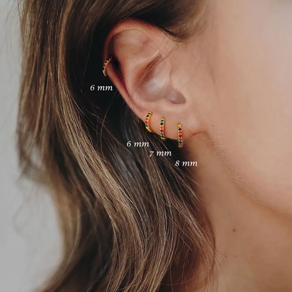 Gold, rose gold, and silver circle-shaped perforated stud earrings on a plain background.