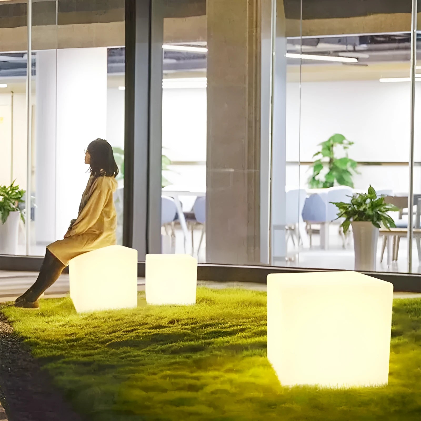 A white square cube LED stool light sitting on a patio, illustrating its modern design and outdoor use.