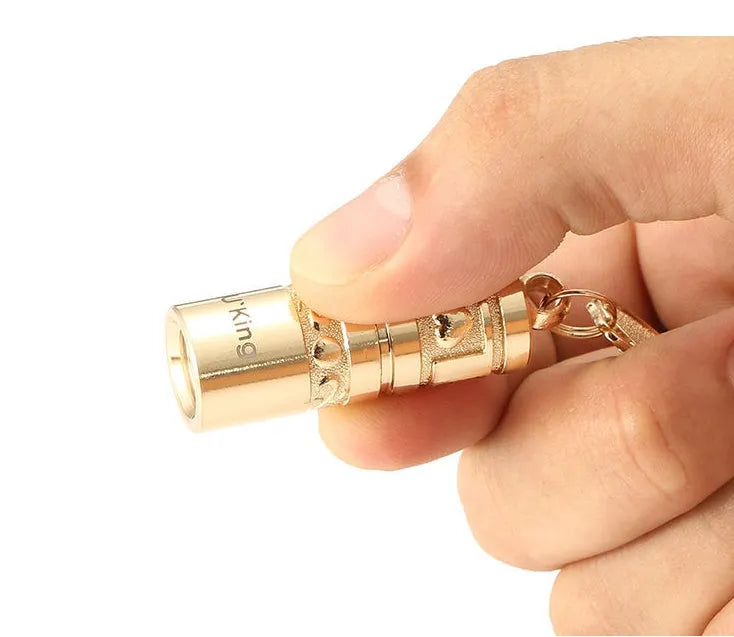 Gold-colour zinc alloy waterproof mini LED flashlight on a keychain ring.
