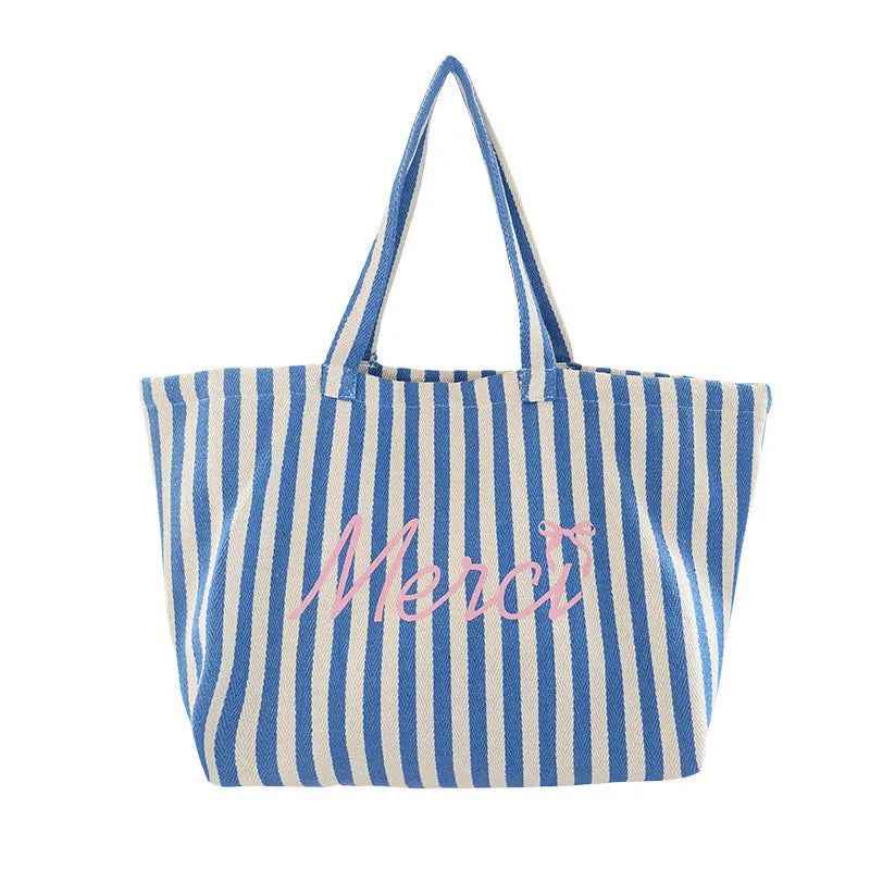 Blue striped letters printed on a pink, blue and white striped cotton canvas bag.