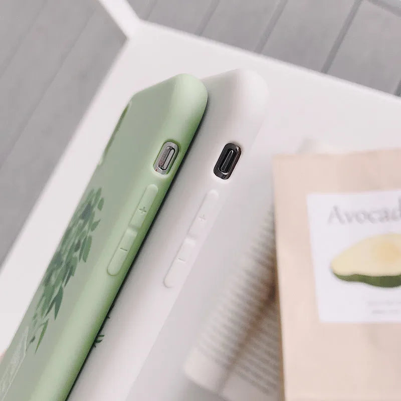 White silicone iPhone case with a detailed painted plant pattern on the back, showing its 360-degree protective edges.