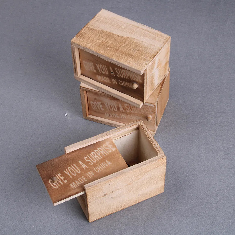 Wooden prank scare box with a lifelike spider figurine on a table.