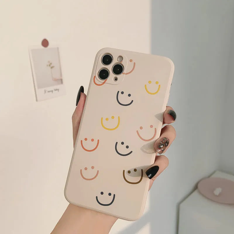 Simple silicone TPU iPhone case with a painted smiley face design on a solid colour background.