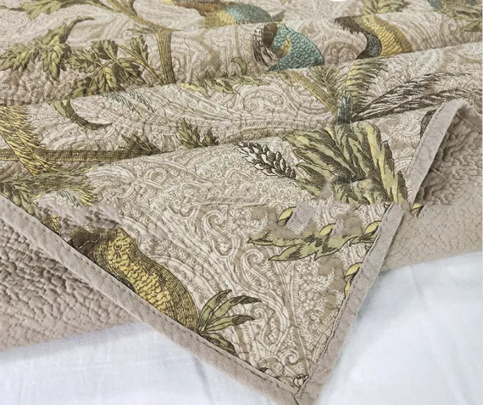 American-style floral quilted cotton bedspread in blue, shown draped on a double bed.