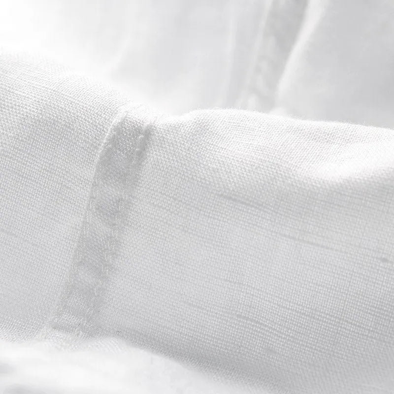 Man wearing a loose-fit light blue linen short sleeve shirt with a square collar, cardigan style.