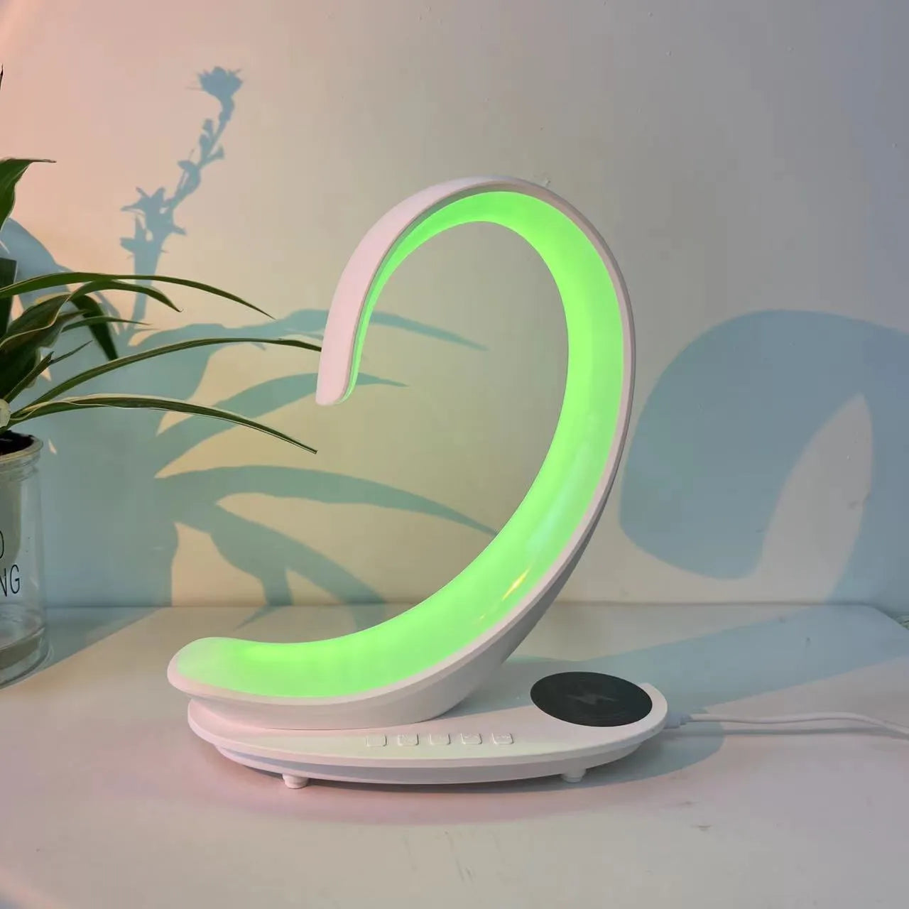 White swan-shaped desktop gadget with wireless charging pad, Bluetooth speaker, and colourful LED atmosphere light.