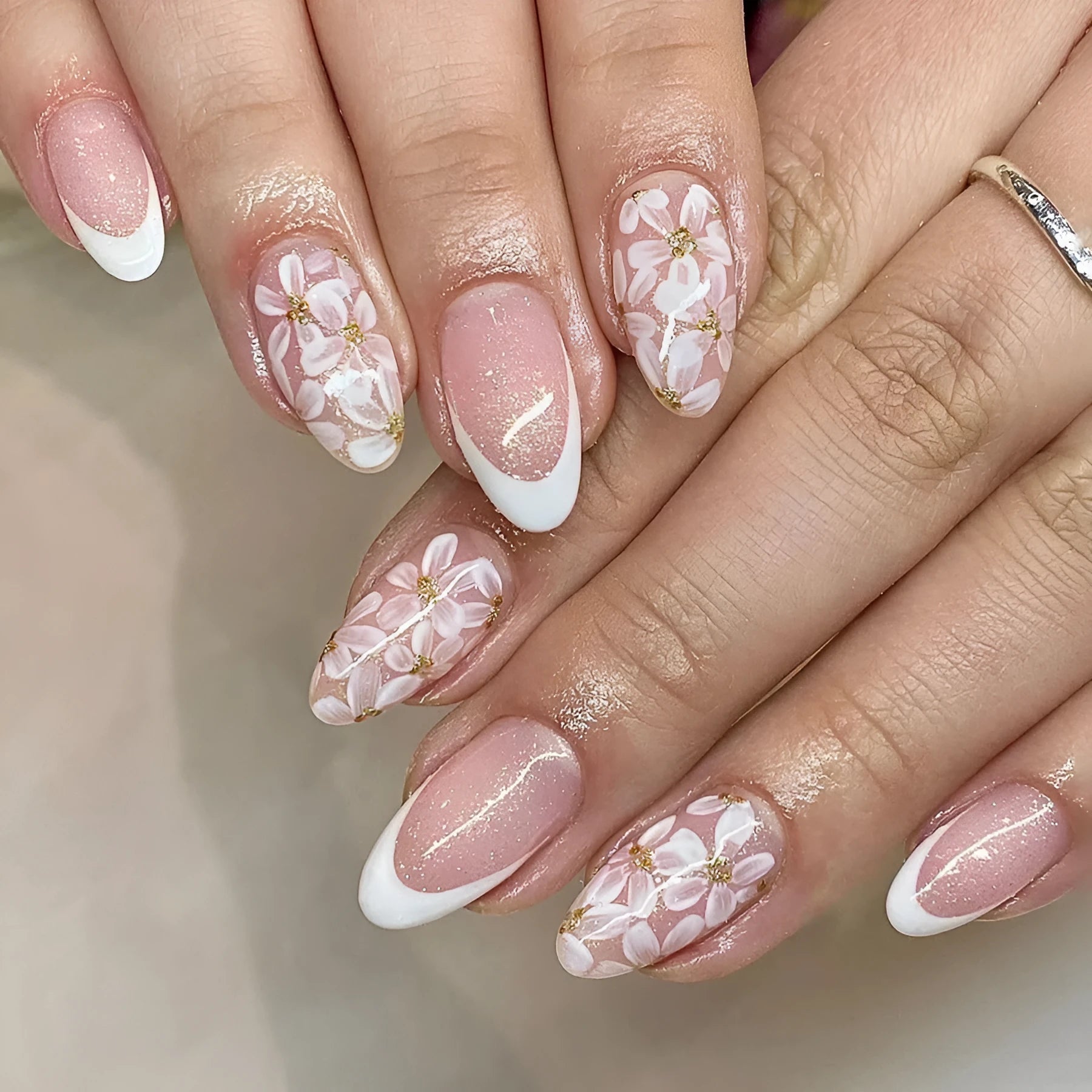 Short almond shaped false nails with glossy finish, glitter, and powder flower design in C625 colour.