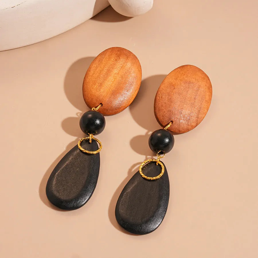 Wooden drop earrings with oval ellipse shape and silver needle accents in brown black colour