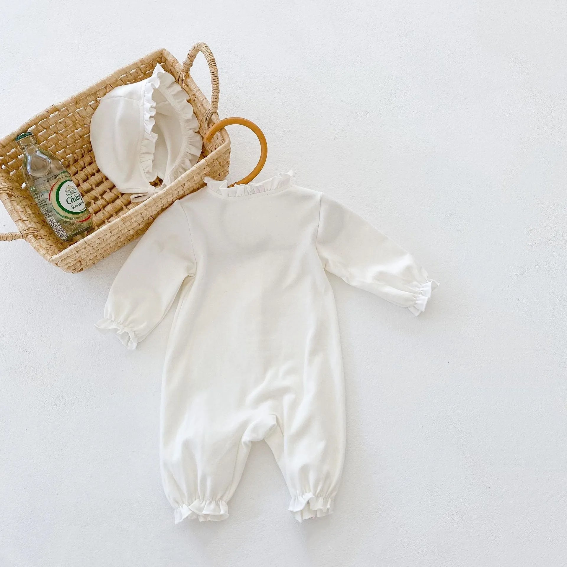 Beige knitted cotton baby jumpsuit with wooden ear collar and lace, long sleeves, hood, on a neutral background