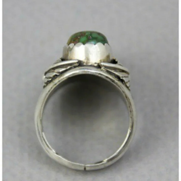 Close-up of a geometric turquoise ring with a retro inlaid design on a hand.