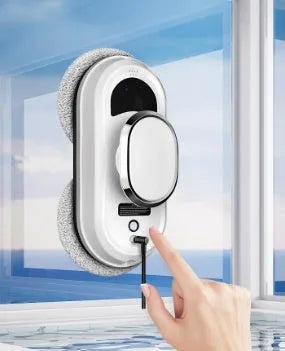 White automatic high-altitude window cleaning machine with remote control on a windowsill.