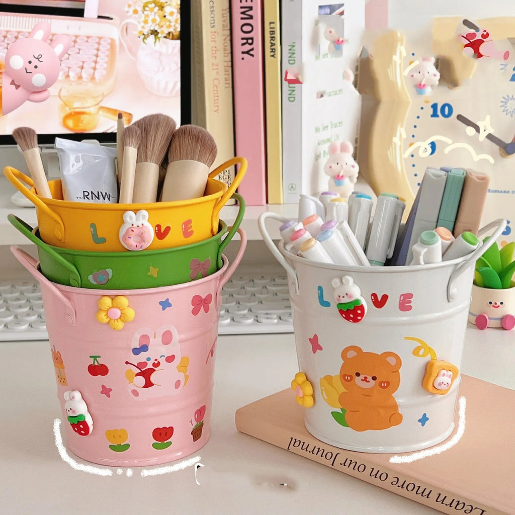 A round metal pen holder in various colours on a desk, holding pens and pencils.