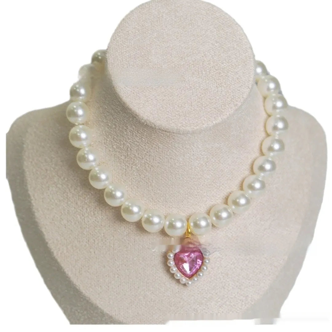 Pearl necklace cat collar with heart-shaped gem charm in various colours on a white background.
